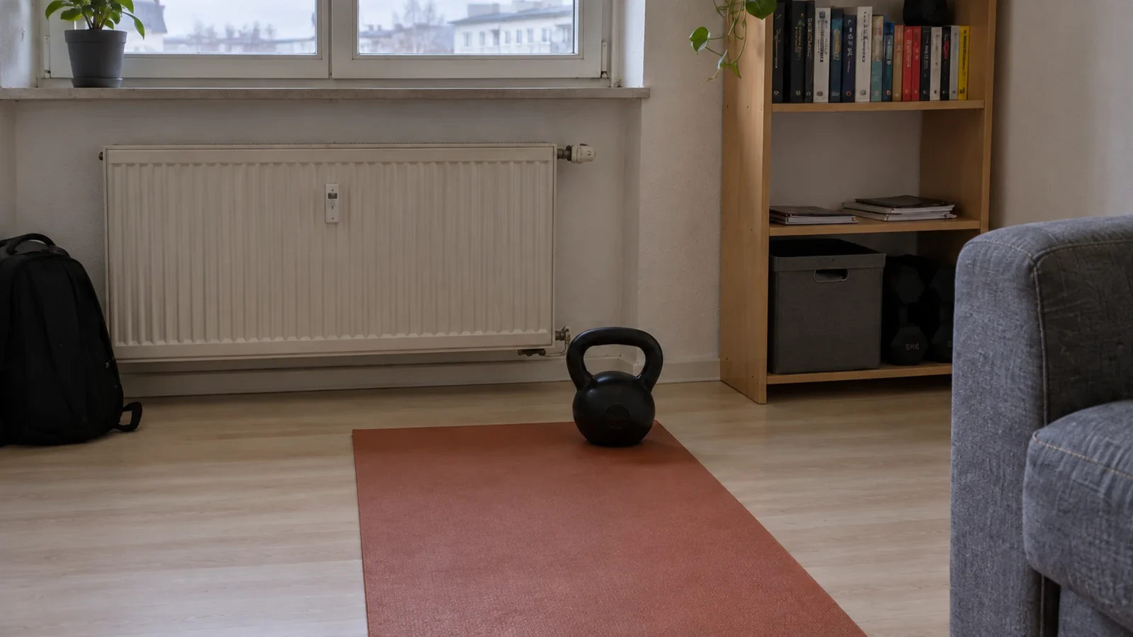 Ausgerollte Matte mit einer Kettlebell im Wohnzimmer, die komplette Ausstattung für Ausgleichssport zum Bürojob zuhause